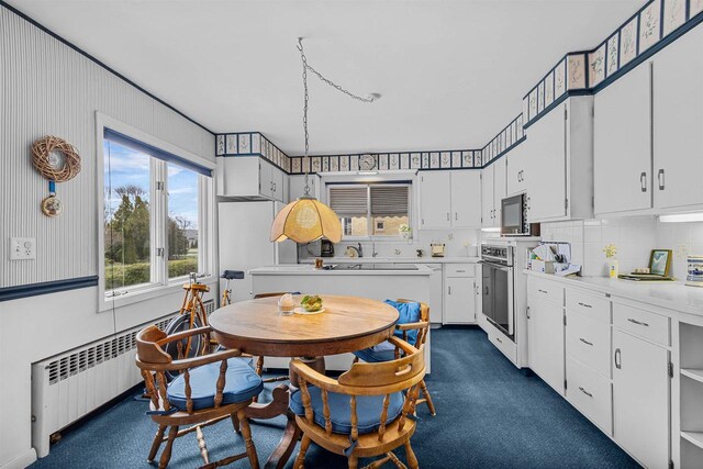 812 Milwaukee St, Kewaunee, WI 54216 - kitchen with radiator, wall oven, light countertops, white cabinetry, and tasteful backsplash