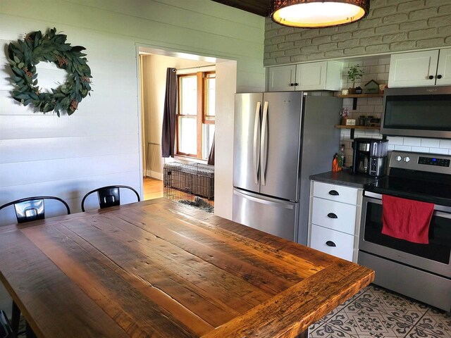 218 7th Ave, New Glarus, WI 53574 - kitchen with dark countertops, open shelves, wood walls, stainless steel appliances, and white cabinetry
