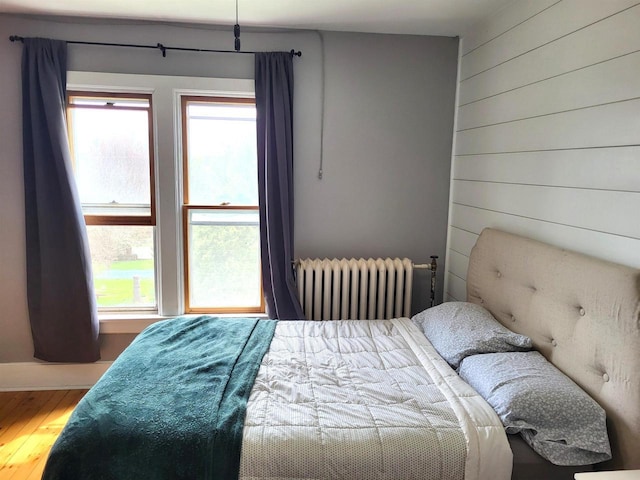 218 7th Ave, New Glarus, WI 53574 - bedroom featuring wood finished floors, wood walls, and radiator heating unit