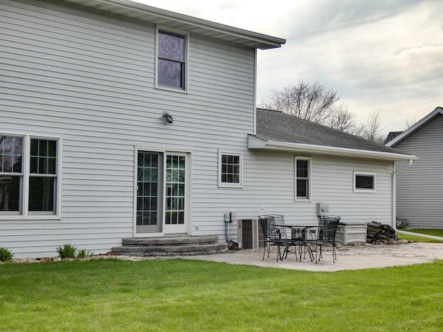 rear view of house featuring a yard, a patio, a shingled roof, and entry steps