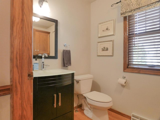 bathroom with vanity, visible vents, wood finished floors, toilet, and baseboards