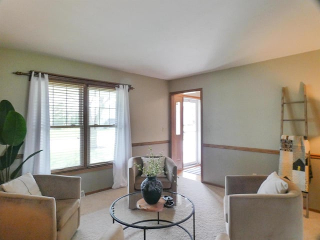 living area featuring baseboards, light carpet, and a wealth of natural light