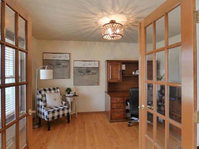 office space featuring baseboards, a chandelier, french doors, and light wood-type flooring