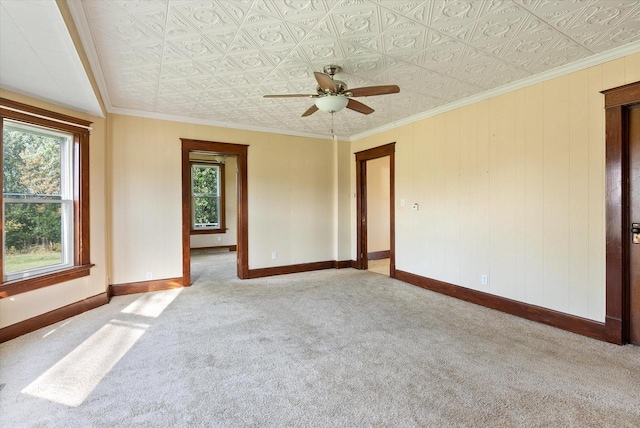 carpeted empty room with baseboards, ceiling fan, an ornate ceiling, and a healthy amount of sunlight