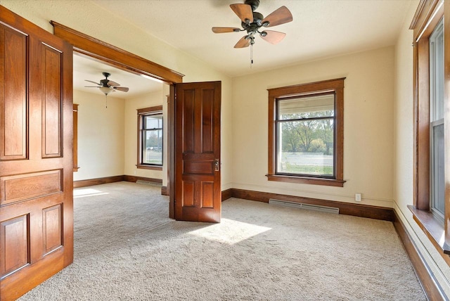 empty room featuring carpet floors, plenty of natural light, baseboards, and a ceiling fan