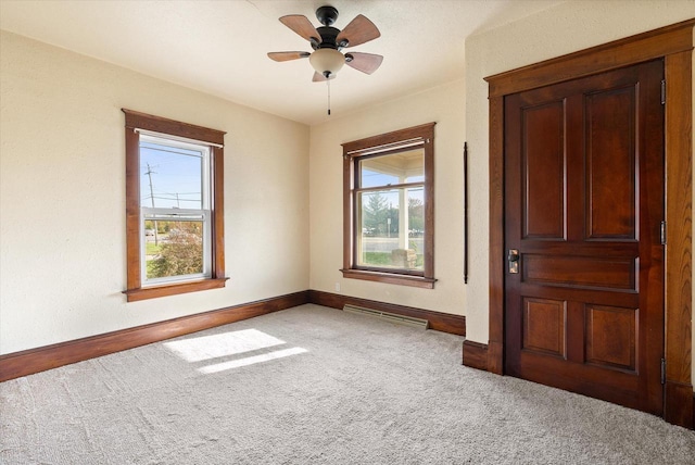 carpeted empty room with baseboards, ceiling fan, and a healthy amount of sunlight
