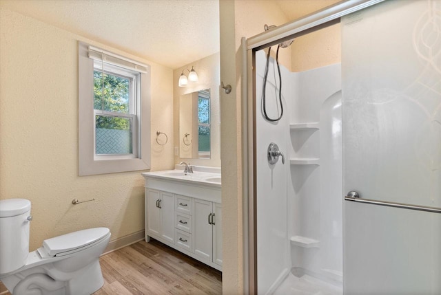 bathroom with vanity, toilet, wood finished floors, and a stall shower