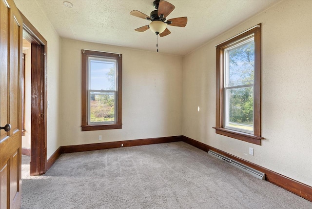 carpeted spare room featuring baseboards, ceiling fan, a wealth of natural light, and baseboard heating