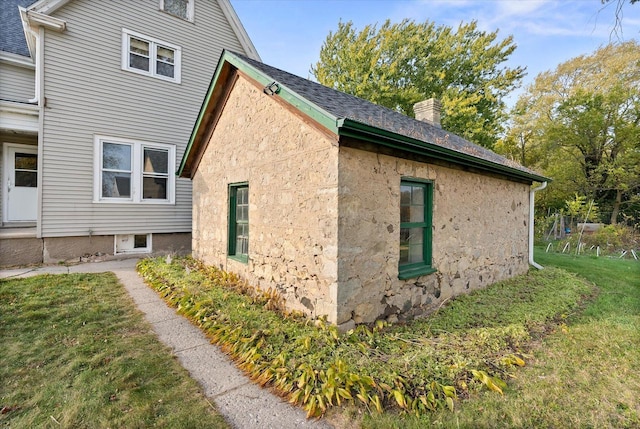 view of side of property with a lawn, a chimney, and stone siding