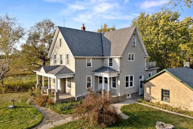 view of front facade featuring a shingled roof, a chimney, a porch, and a front lawn