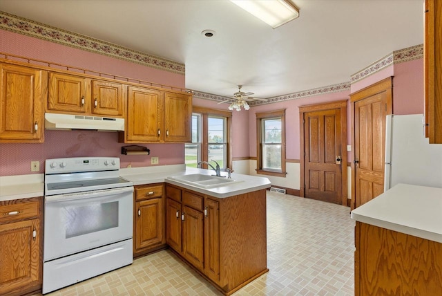kitchen with brown cabinets, a sink, white appliances, a peninsula, and under cabinet range hood