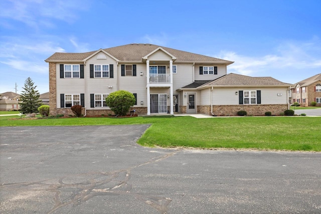 traditional-style house with brick siding, a balcony, and a front yard