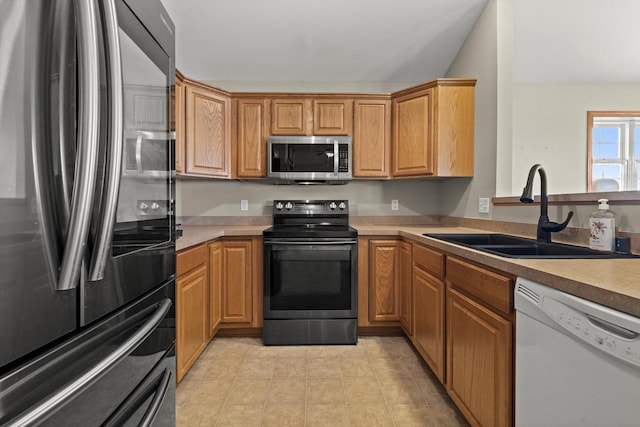 kitchen with light countertops, light tile patterned flooring, appliances with stainless steel finishes, and a sink