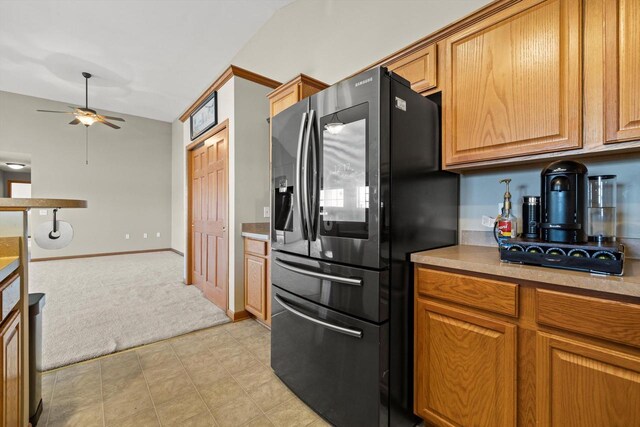 kitchen featuring light countertops, a ceiling fan, refrigerator with ice dispenser, and brown cabinetry