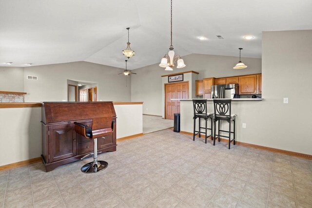 kitchen with baseboards, freestanding refrigerator, vaulted ceiling, and a breakfast bar