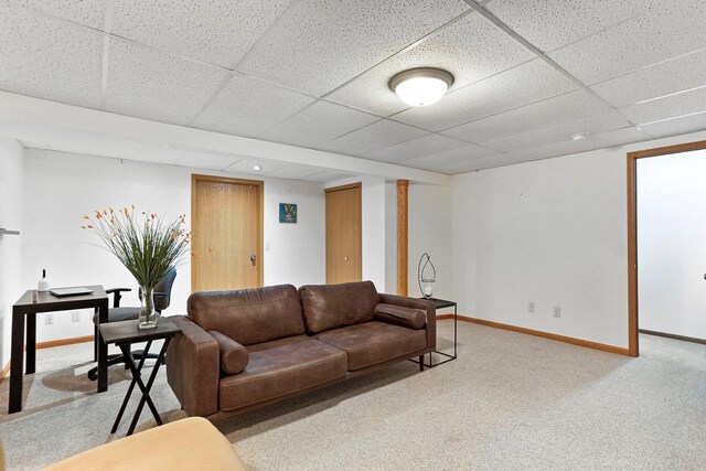 carpeted living area with baseboards and a drop ceiling