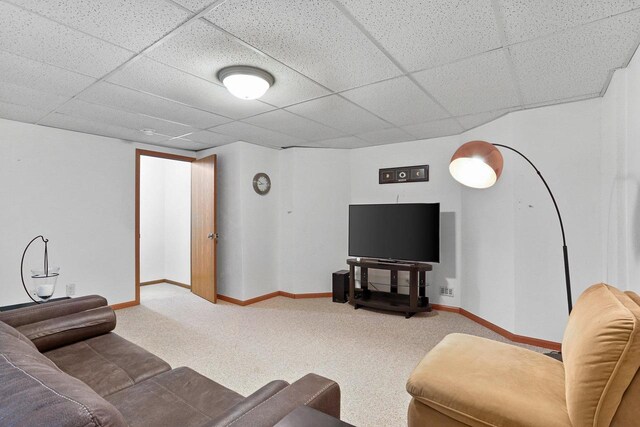 carpeted living area with baseboards and a drop ceiling