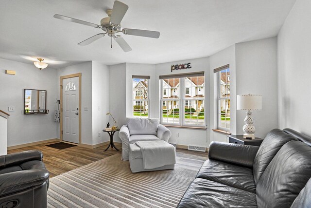 living room featuring baseboards, ceiling fan, wood finished floors, and visible vents