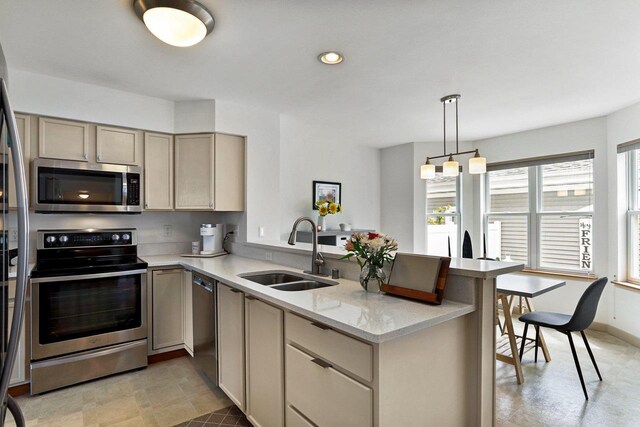 kitchen featuring a peninsula, recessed lighting, light stone counters, a sink, and appliances with stainless steel finishes