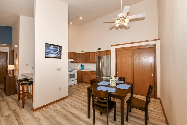 dining area with high vaulted ceiling, a ceiling fan, and light wood finished floors