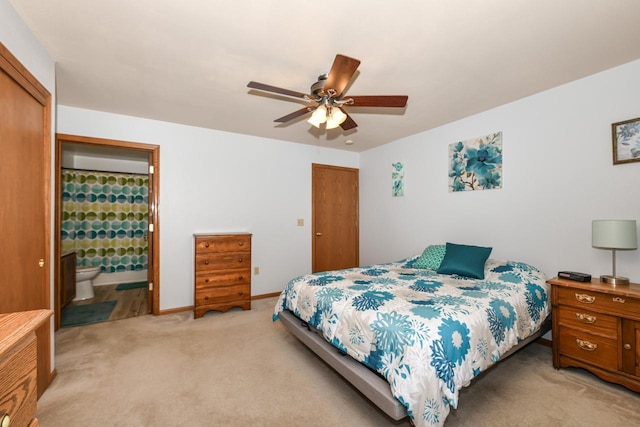 bedroom with ceiling fan, light colored carpet, baseboards, a closet, and connected bathroom