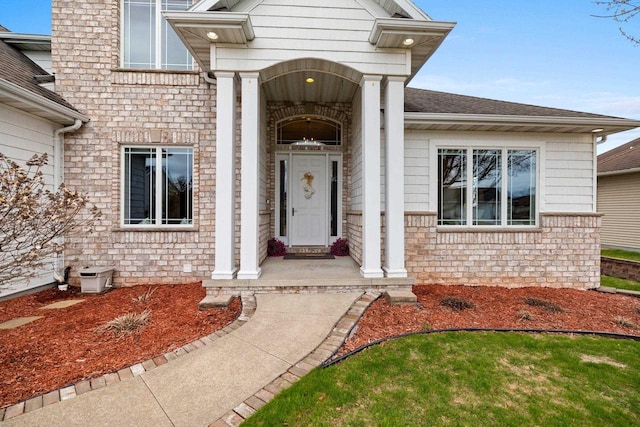 entrance to property with brick siding and roof with shingles
