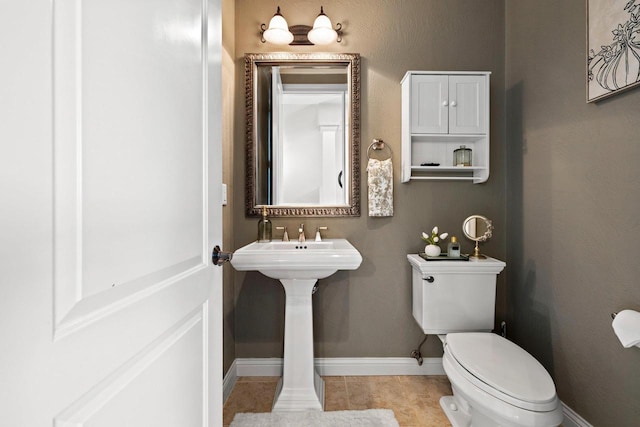 half bathroom featuring baseboards, tile patterned flooring, and toilet