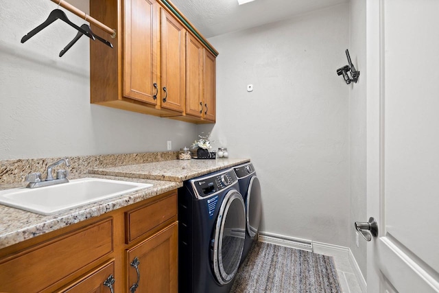 clothes washing area featuring washer and dryer, baseboards, a sink, and cabinet space