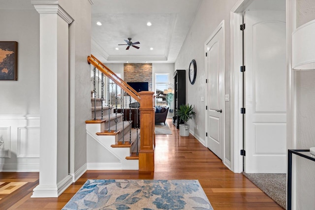 foyer entrance with ceiling fan, recessed lighting, wood finished floors, ornate columns, and stairway