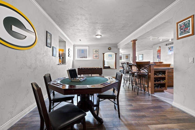 dining room with ornate columns, baseboards, a textured wall, and wood finished floors