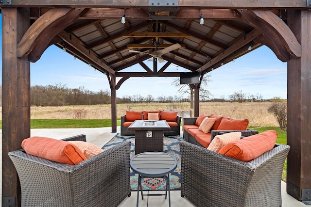 view of patio with a gazebo, a ceiling fan, an outdoor living space with a fire pit, and a rural view