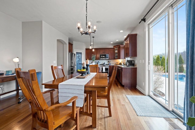 dining room with an inviting chandelier, a healthy amount of sunlight, and light wood-style floors