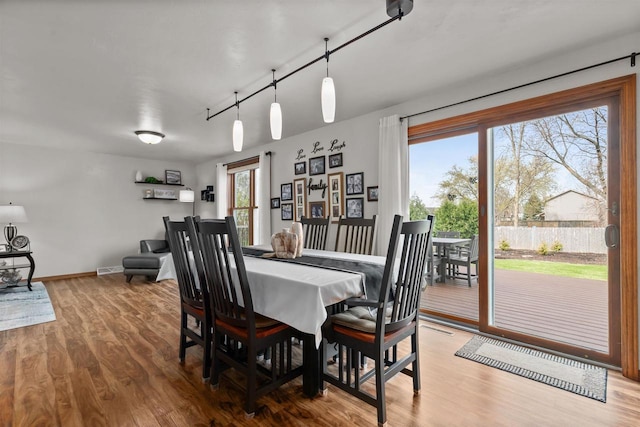 dining area featuring baseboards, track lighting, and wood finished floors
