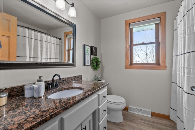 full bathroom featuring visible vents, vanity, wood finished floors, toilet, and baseboards