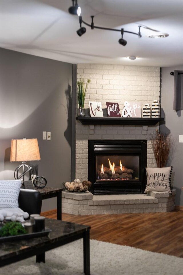 living area featuring baseboards, wood finished floors, and a fireplace