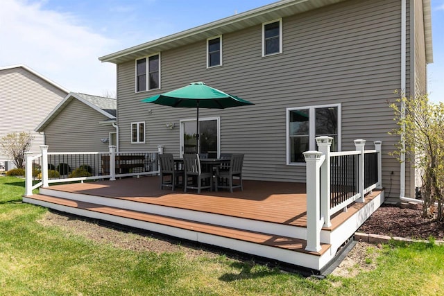 back of property with a lawn, outdoor dining area, and a deck