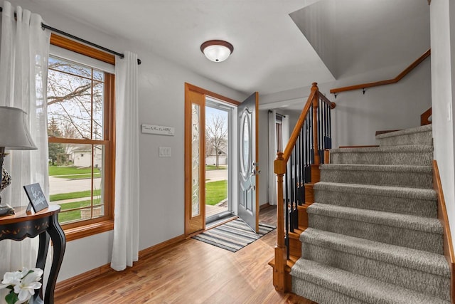 foyer with baseboards, wood finished floors, and stairway