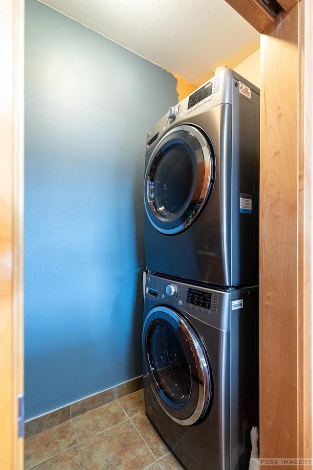 laundry area featuring baseboards, laundry area, tile patterned floors, and stacked washer / dryer