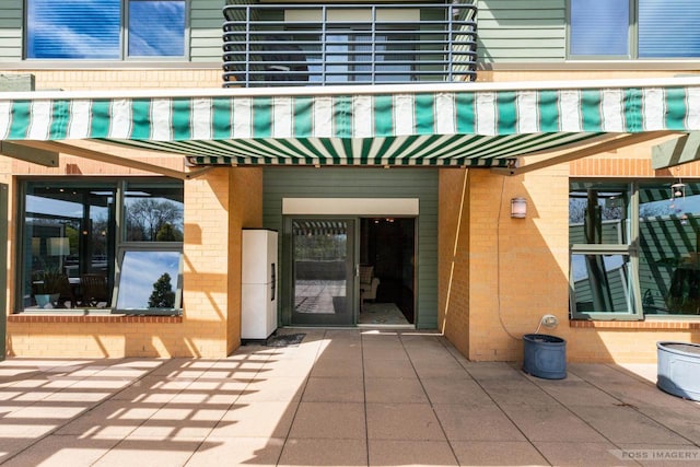 entrance to property featuring brick siding and a balcony