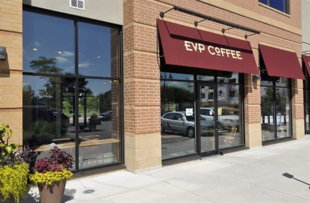 view of exterior entry featuring brick siding and visible vents