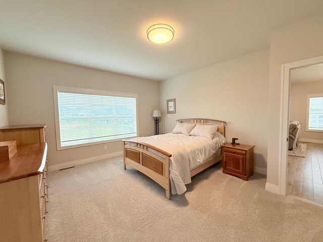 bedroom with baseboards and light colored carpet