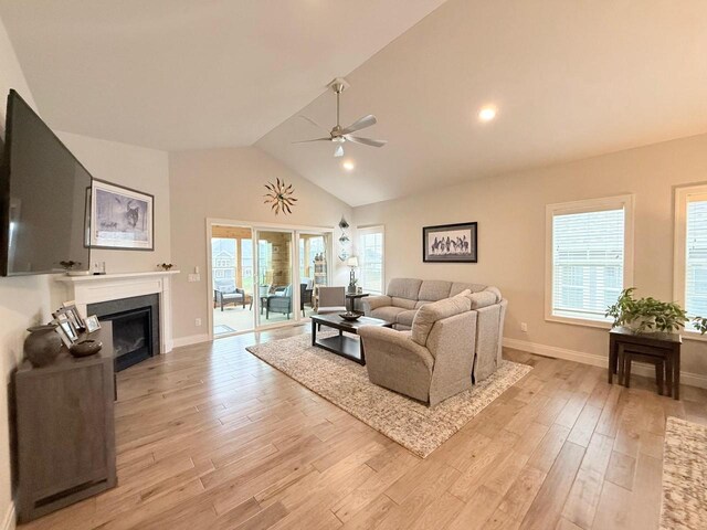 living room with light wood finished floors, a glass covered fireplace, a ceiling fan, baseboards, and recessed lighting