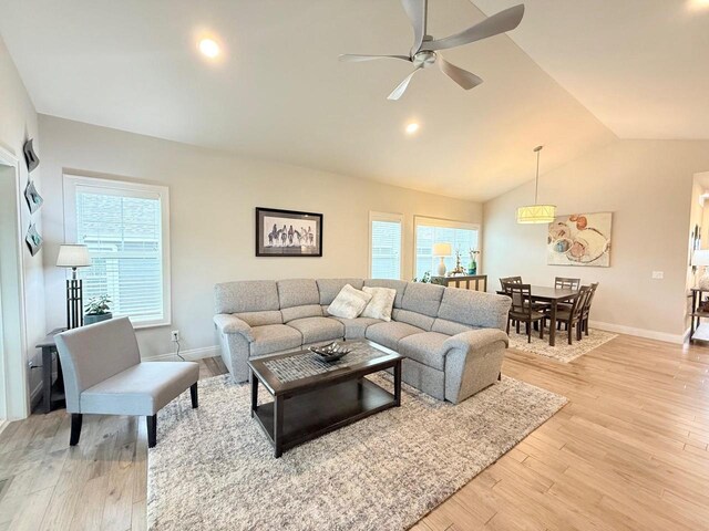 living room featuring light wood-style floors, baseboards, ceiling fan, and vaulted ceiling