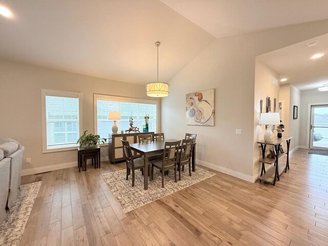 dining space featuring visible vents, baseboards, lofted ceiling, and light wood finished floors