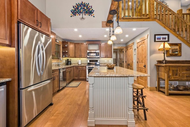 W5929 Driftwood Ln, New Lisbon, WI 53950 - kitchen with stainless steel appliances, light wood-style flooring, open shelves, light stone countertops, and a kitchen bar