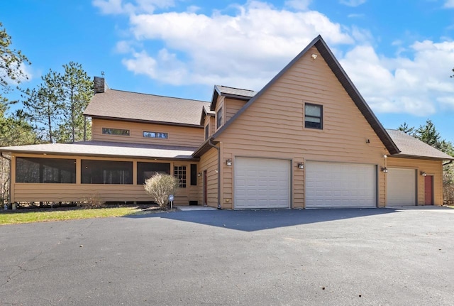 W5929 Driftwood Ln, New Lisbon, WI 53950 - view of front of home with a sunroom, a chimney, driveway, an attached garage, and roof with shingles