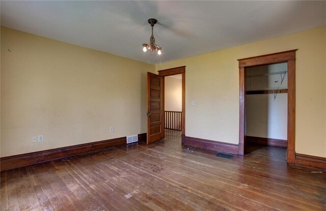 1725 Meadow Hill Dr, Menomonie, WI 54751 - unfurnished bedroom with a notable chandelier, hardwood / wood-style floors, baseboards, visible vents, and a closet