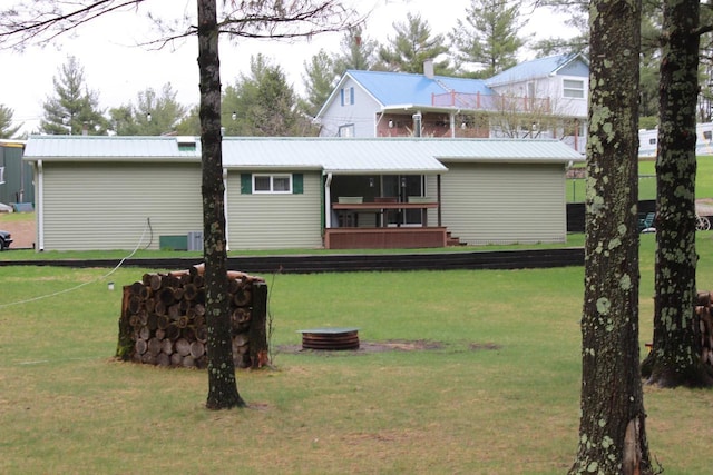 back of property featuring a yard and metal roof