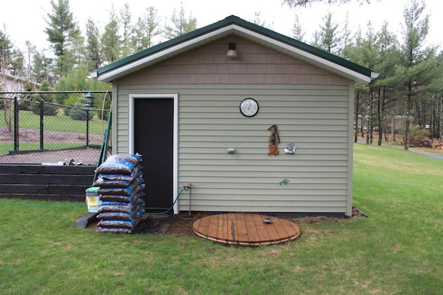 view of outdoor structure with fence and an outbuilding