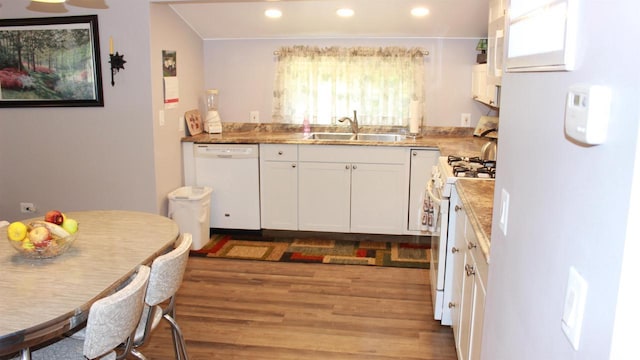 kitchen featuring white appliances, light wood-style floors, recessed lighting, white cabinets, and a sink